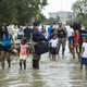 Families walk out of the water in west Houston on Aug. 30, 2017, after being rescued from their flooded homes and apartments because of Hurricane Harvey. (Erich Schlegel/Getty Images)